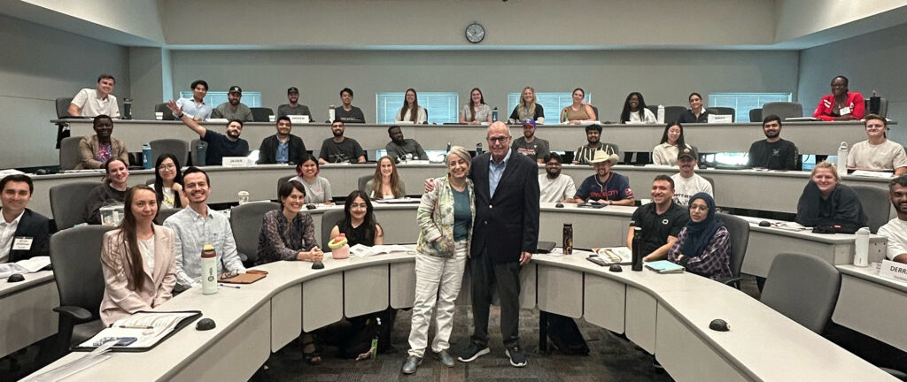 Lisa Shatz and Richard M. Bowen stand with Cohort MBA students in a UT Dallas classroom.