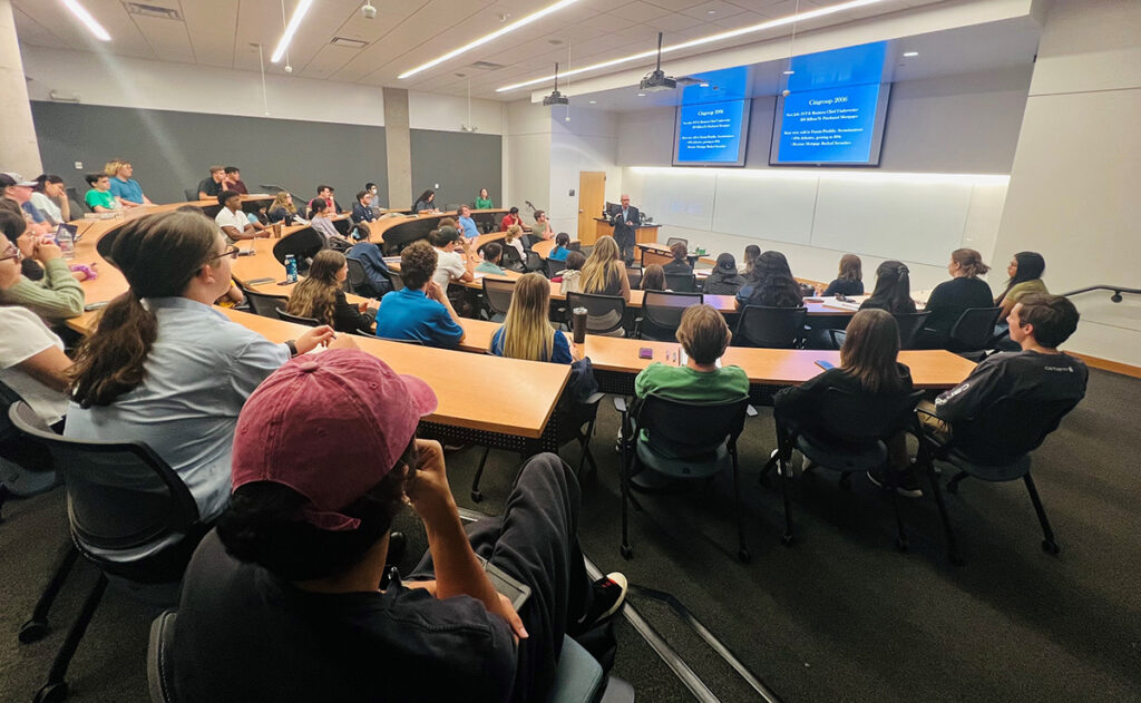 Image of Richard M. Bowen at the front of the room with students filling the long, curved stadium seating tables.