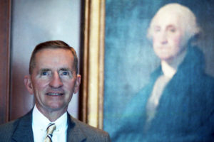 Color portrait of Ross Perot, 1986, standing in front of a portrait of George Washington