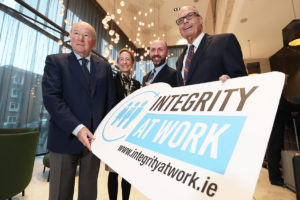 Picture of Justice John Hedigan, Caoimhe de Barra, John Devitt, and Richard Bowen holding an Integrity at Work sign.