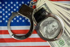 Image of handcuffs, $100 bills and an American flag.