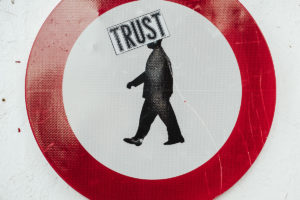 Image of a man walking to the left inside a circle, the word TRUST in a box across his head.