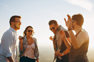 Picture of three men and one woman laughing during daytime.