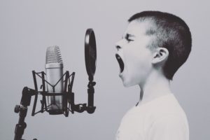 Image: boy singing into microphone with a pop filter