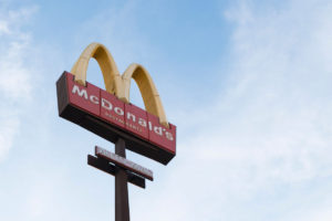 Image looking up at a McConalds sign against a blue sky from the ground.